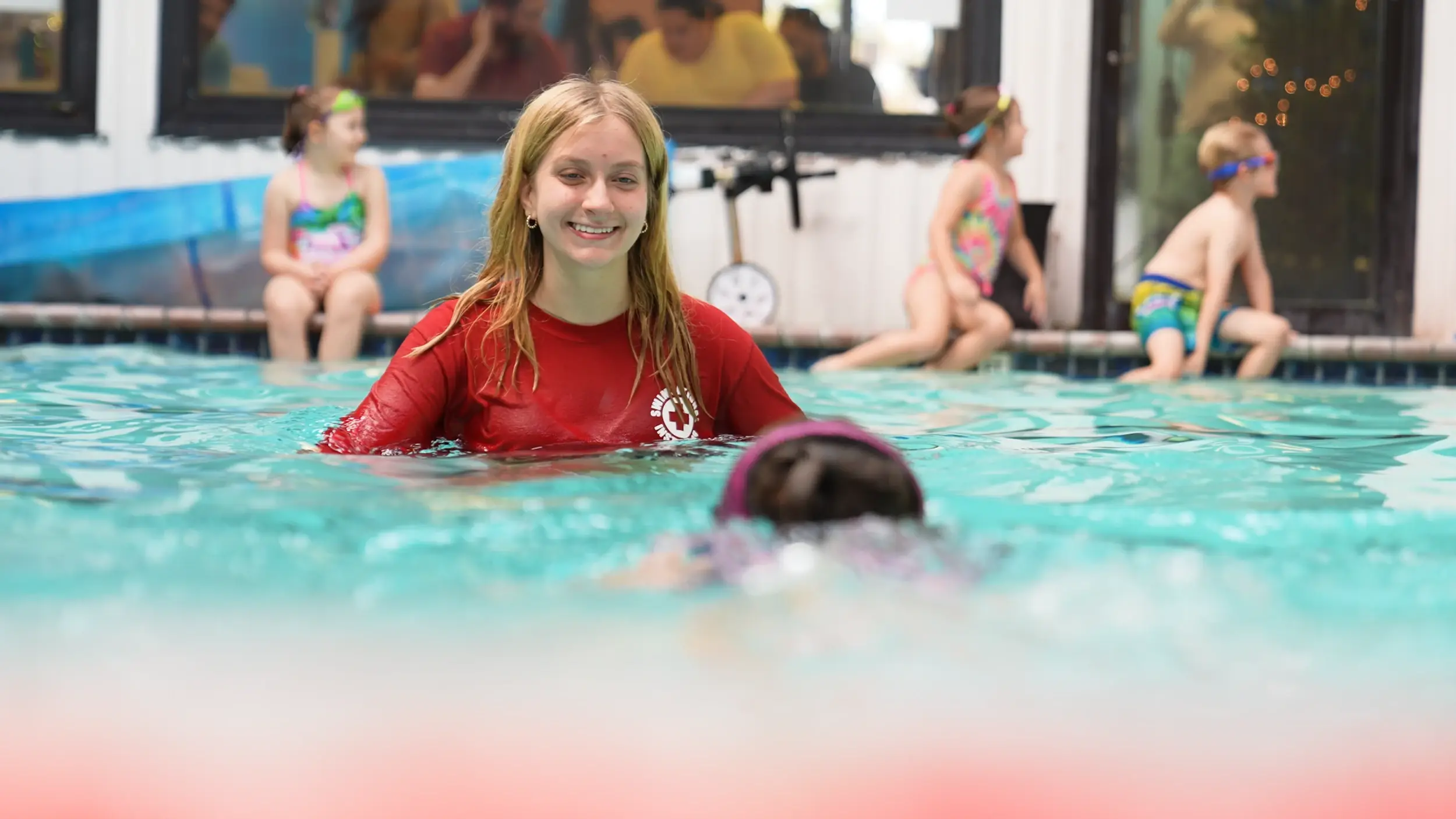 A smiling Swimsational instructor in the pool, ready to welcome a young swimmer